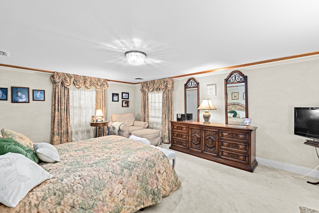 443 Chestnut Street Newton, MA 02468 - Photo 19 of 28 a spacious bedroom with a bed a mirror on dresser and a flat screen tv