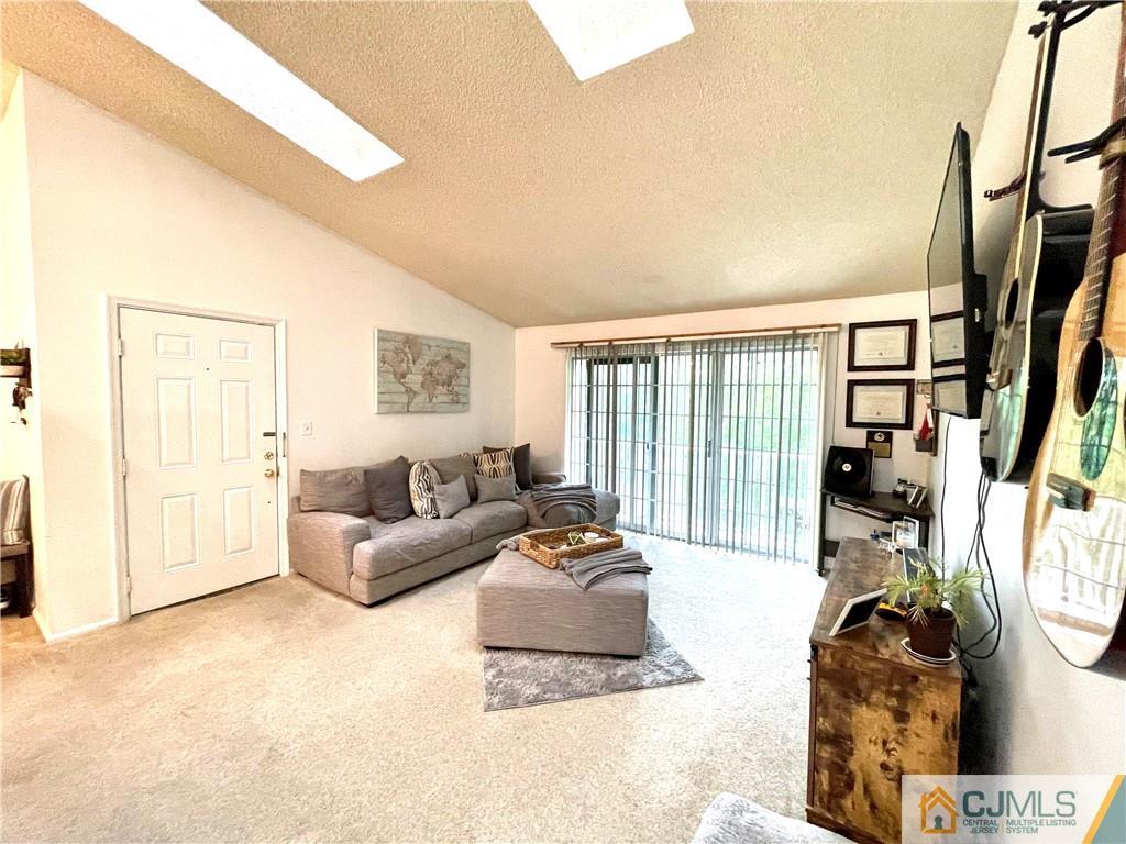341 Wimbeldon Court North Brunswick, NJ 08902 - Photo 3 of 16 a living room with furniture a floor to ceiling window and a flat screen tv