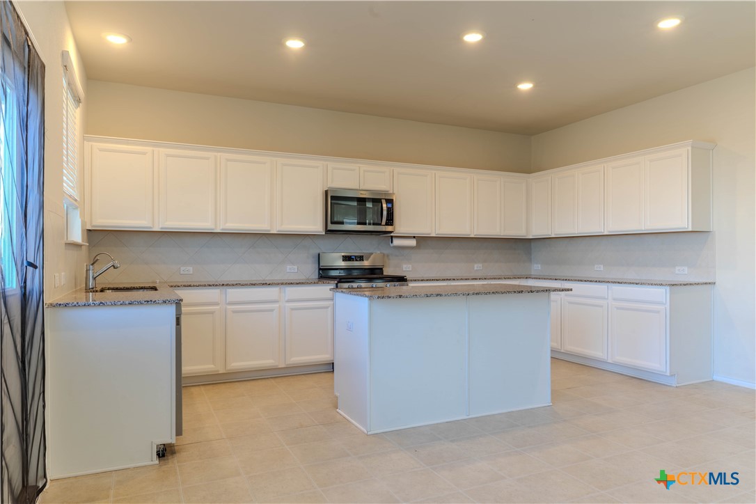 620 English Oak Street Georgetown, TX 78626 - Photo 7 of 29 a kitchen with granite countertop white cabinets and stainless steel appliances
