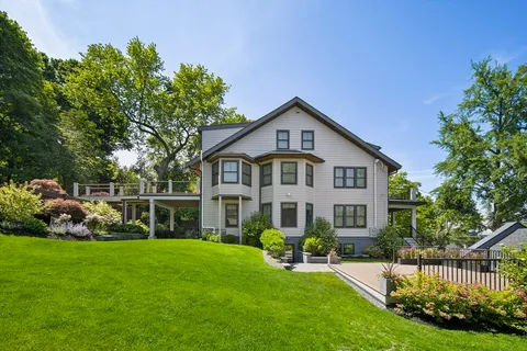 a front view of a house with a garden and trees