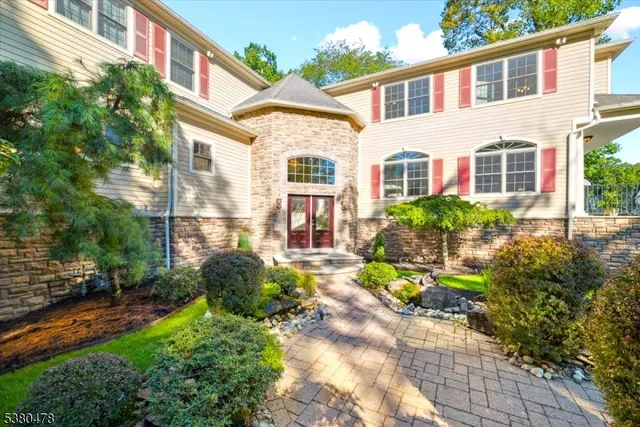 a view of a brick house with many windows plants and large trees