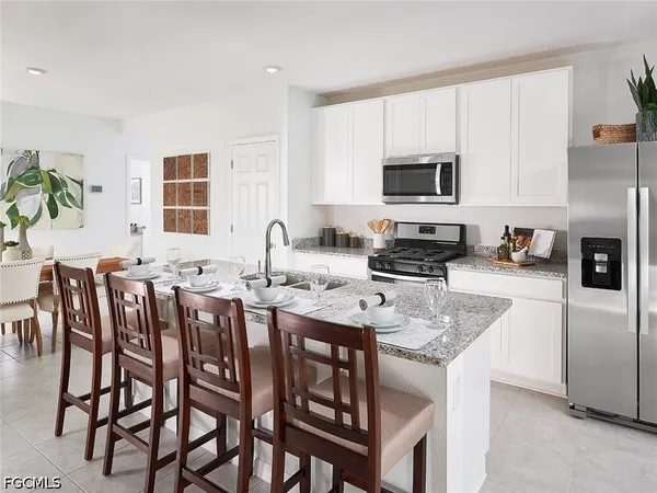 a kitchen with stainless steel appliances granite countertop a stove a sink a refrigerator a dining table and chairs