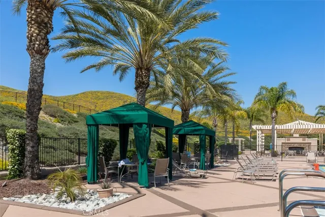 a view of a patio with a table and chairs under an umbrella with palm trees