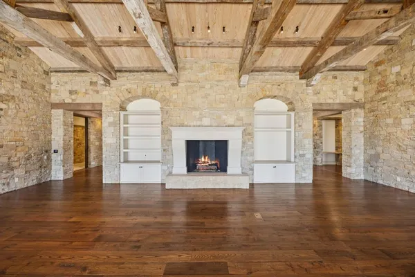 a view of a hall with wooden floors and a fireplace