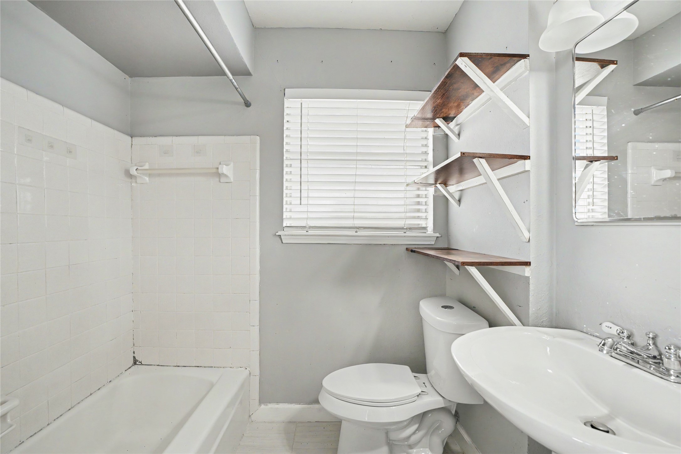 8330 Springtime Lane Houston, TX 77075 - Photo 12 of 27 Primary bathroom with a classic white tile shower, sleek pedestal sink, and convenient built-in shelving for storage.