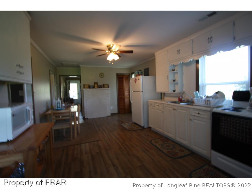 1063 Carl Freeman Road Stedman, NC 28391 - Photo 16 of 17 a open kitchen with cabinets a sink dishwasher a stove and a refrigerator with wooden floor