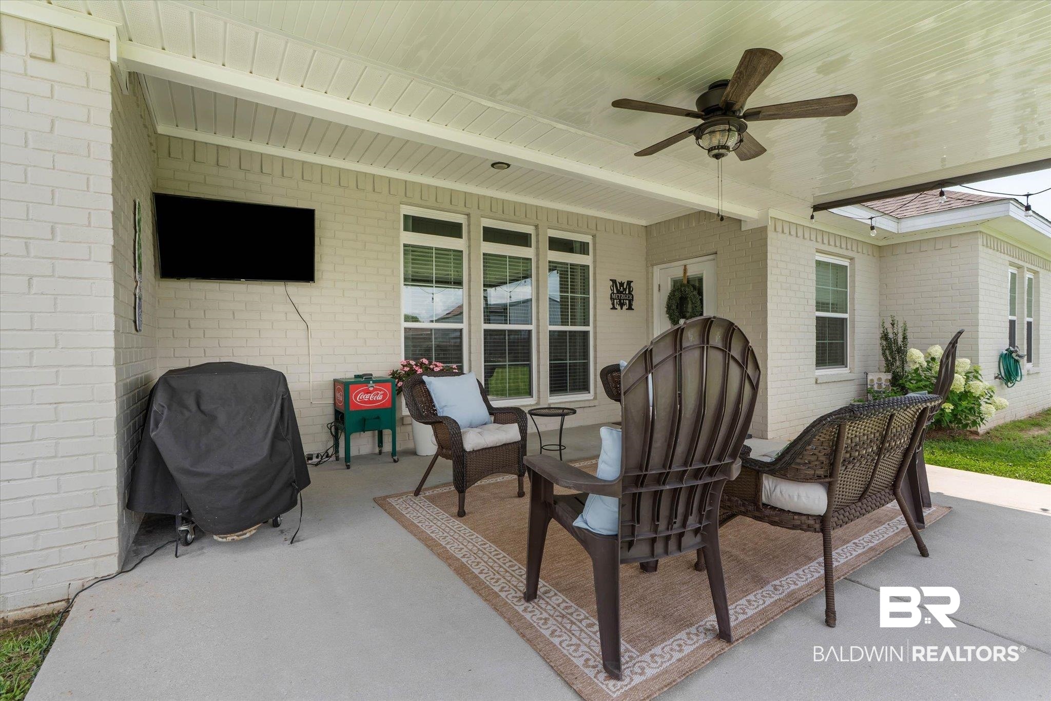 9074 Moses Way Theodore, AL 36582 - Photo 44 of 52 Covered concrete patio with white painted brick exterior, multiple windows, a ceiling fan, and string lighting