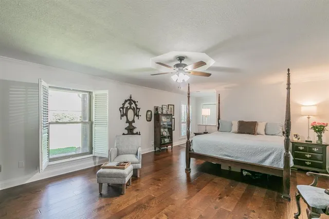 a bedroom with a bed window and walk in closet with wooden floor