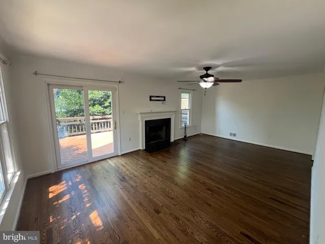 an empty room with wooden floor fireplace and windows