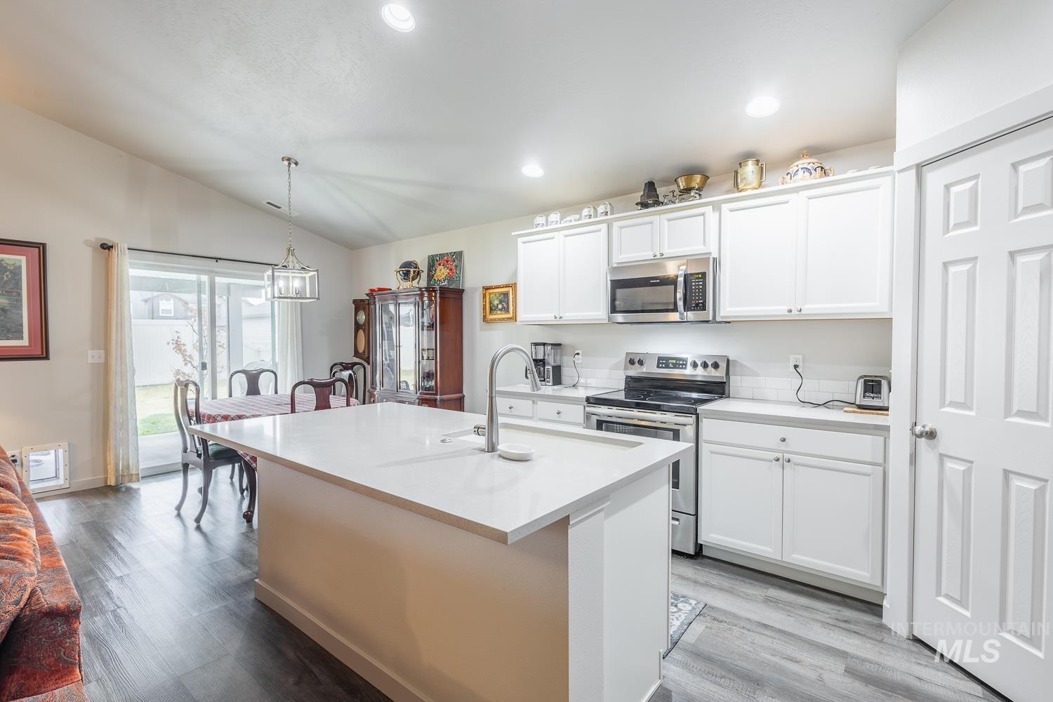11309 West Viola Street Nampa, ID 83651 - Photo 17 of 37 Kitchen featuring stainless steel appliances, white cabinets, hanging light fixtures, vaulted ceiling, and light wood-style floors