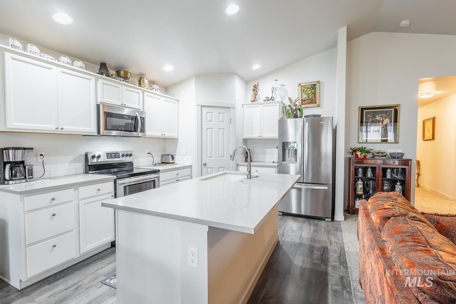 11309 West Viola Street Nampa, ID 83651 - Photo 18 of 37 Kitchen with stainless steel appliances, vaulted ceiling, light wood-style floors, an island with sink, and white cabinets