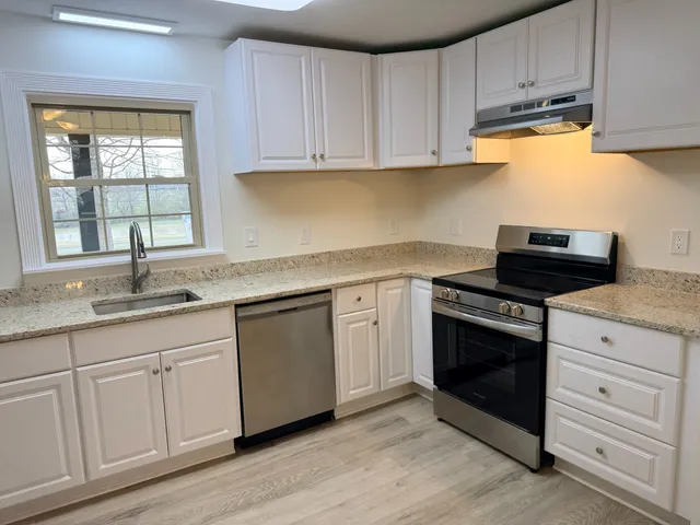 a bathroom with a granite countertop sink a window and a rug