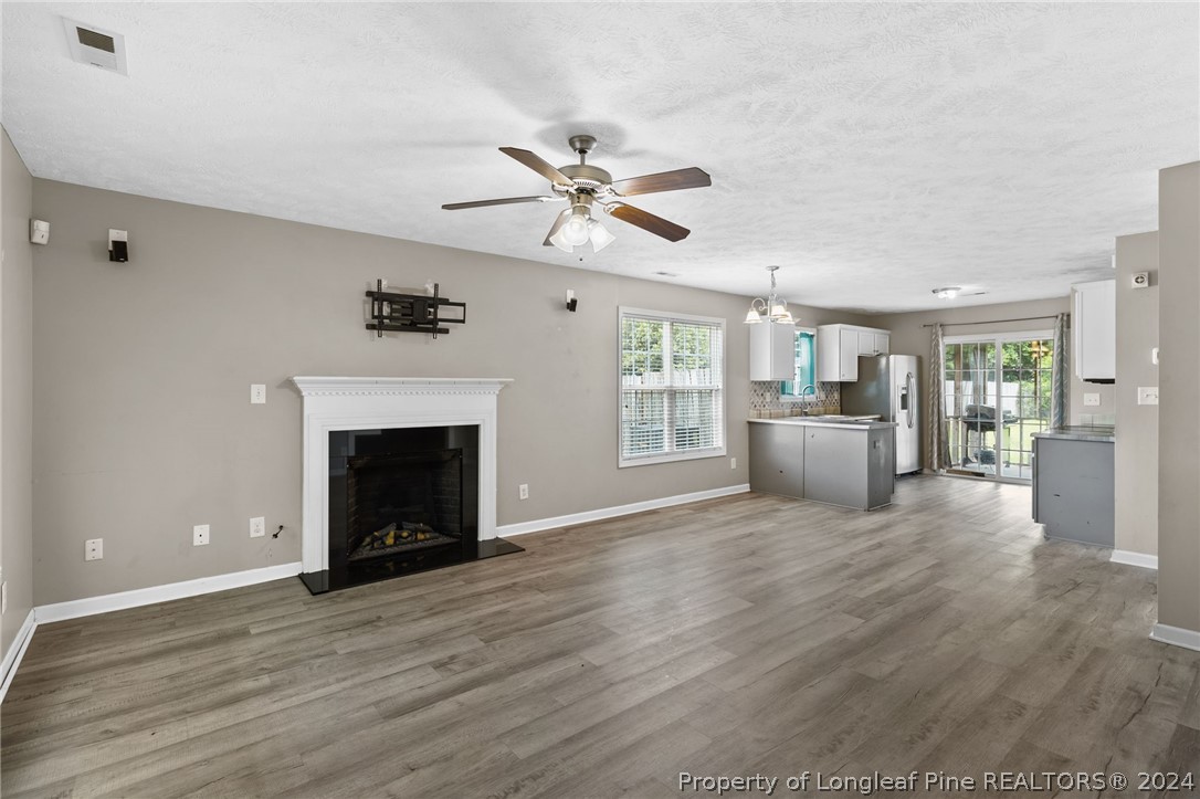 519 Cape Fear Road Raeford, NC 28376 - Photo 5 of 39 a view of a livingroom with a fireplace a ceiling fan and a kitchen view