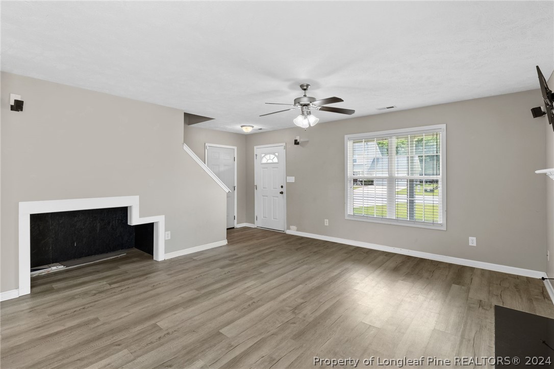 519 Cape Fear Road Raeford, NC 28376 - Photo 6 of 39 an empty room with wooden floor fireplace and windows