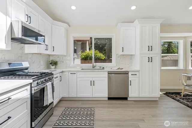a kitchen with stainless steel appliances white cabinets and a stove top oven
