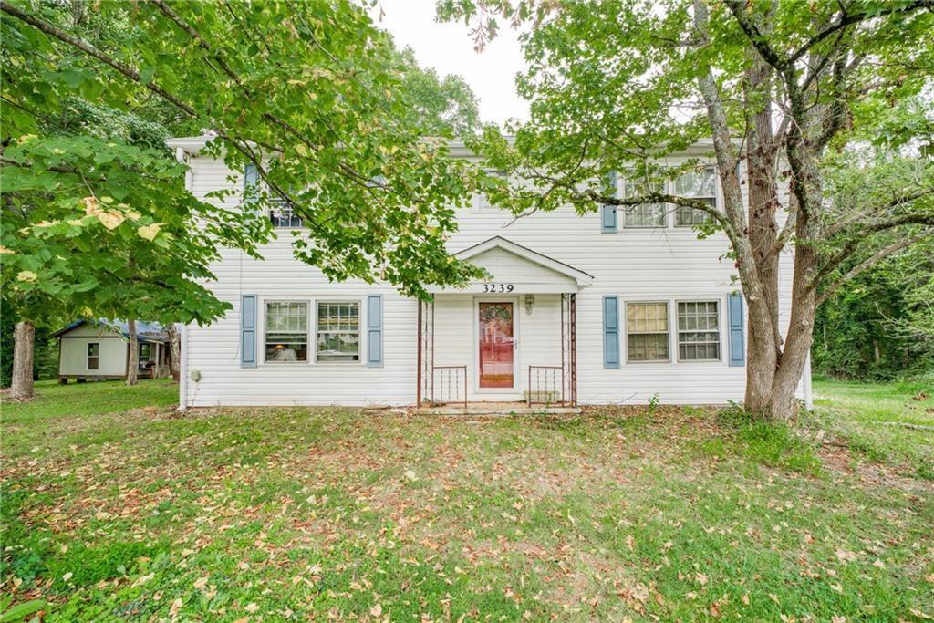 a front view of house with yard and trees in the background