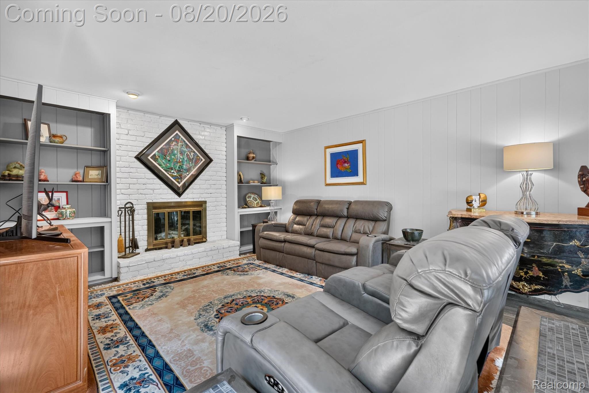 6235 Waldon Road Clarkston, MI 48346 - Photo 12 of 41 Whitewashed brick fireplace with a brass firebox, flanked by built-in shelving and cabinetry