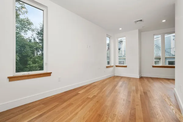 an empty room with wooden floor and windows