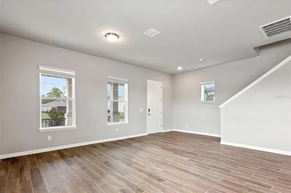 a view of empty room with wooden floor and fan