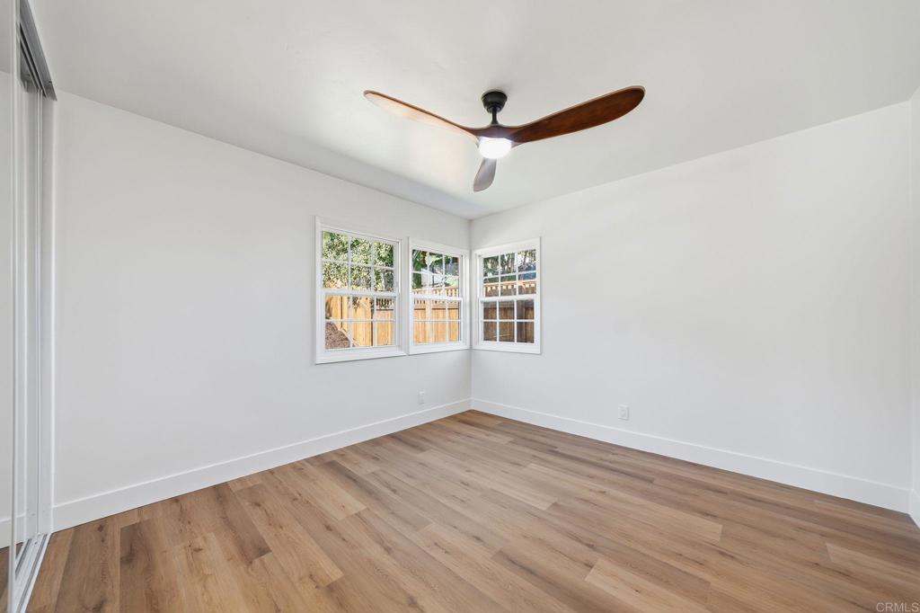 4920 Elsa Road San Diego, CA 92120 - Photo 28 of 46 an empty room with wooden floor ceiling fan and windows