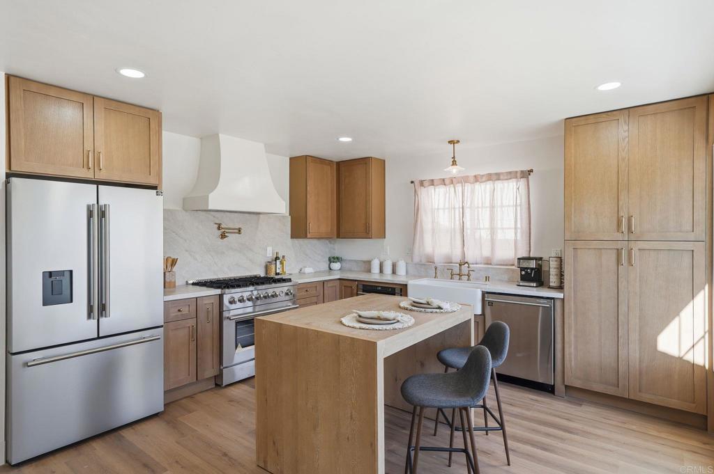 4920 Elsa Road San Diego, CA 92120 - Photo 8 of 46 a kitchen with a sink a refrigerator a stove and white cabinets with wooden floor