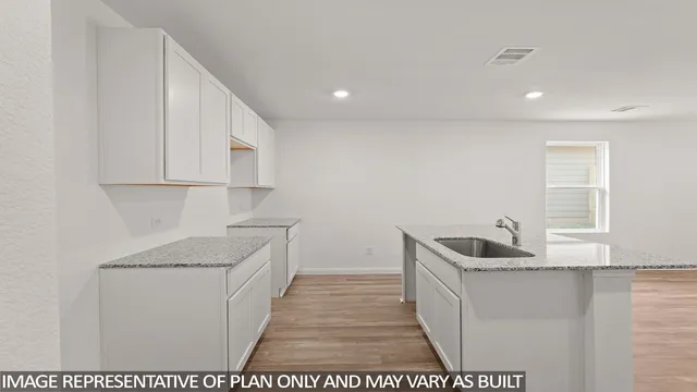 a hallway with granite countertop a sink a stove a refrigerator and cabinets
