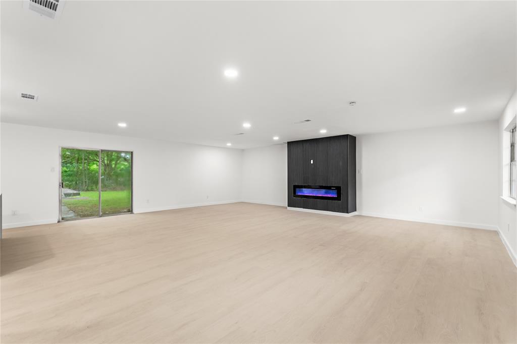 110 Hackberry Street Lancaster, TX 75146 - Photo 8 of 32 Expansive room featuring light wood-finish flooring and a built-in wall unit with an electric fireplace