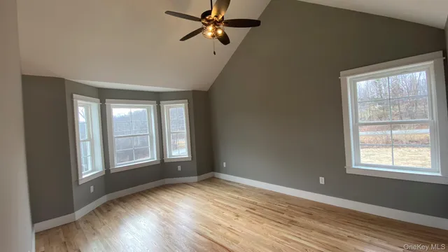 a view of empty room with wooden floor and fan