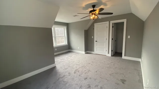 an empty room with closet and a chandelier fan