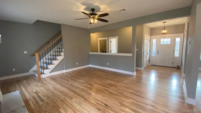 a view of an empty room with window and wooden floor