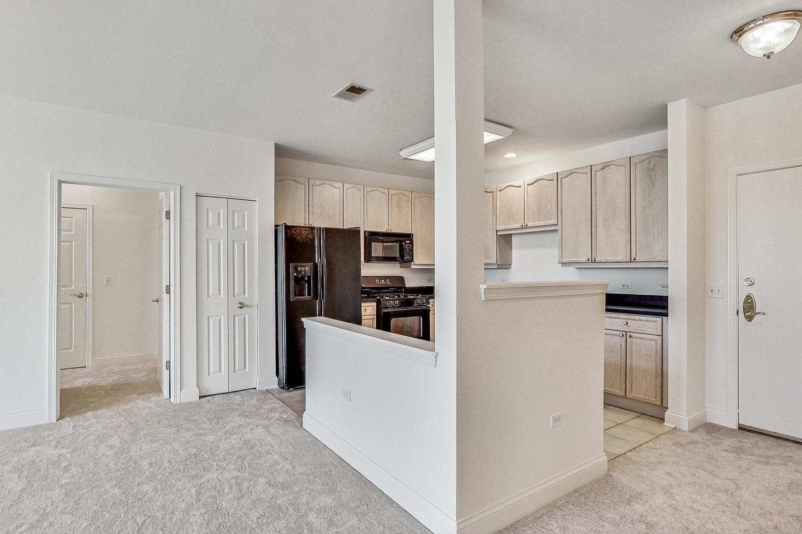 620 McHenry Road, Unit 407 Wheeling, IL 60090 - Photo 7 of 23 a open kitchen with white cabinets and stainless steel appliances