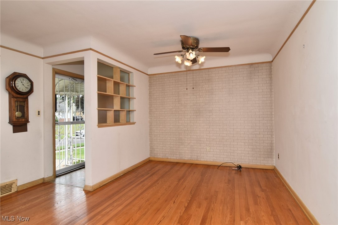9421 David Road Cleveland, OH 44125 - Photo 10 of 36 Spare room featuring brick wall, wood finished floors, and a ceiling fan