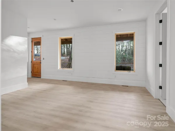 a view of an empty room with window and wooden floor