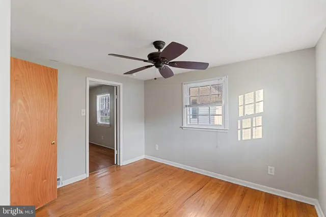 a view of a livingroom with a hardwood floor a ceiling fan and a window