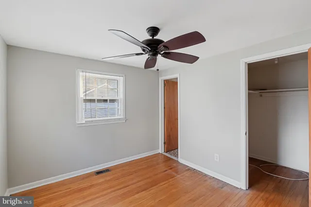 a view of an empty room with closet and wooden floor