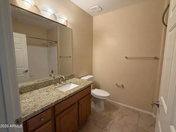a bathroom with a granite countertop sink toilet and a mirror