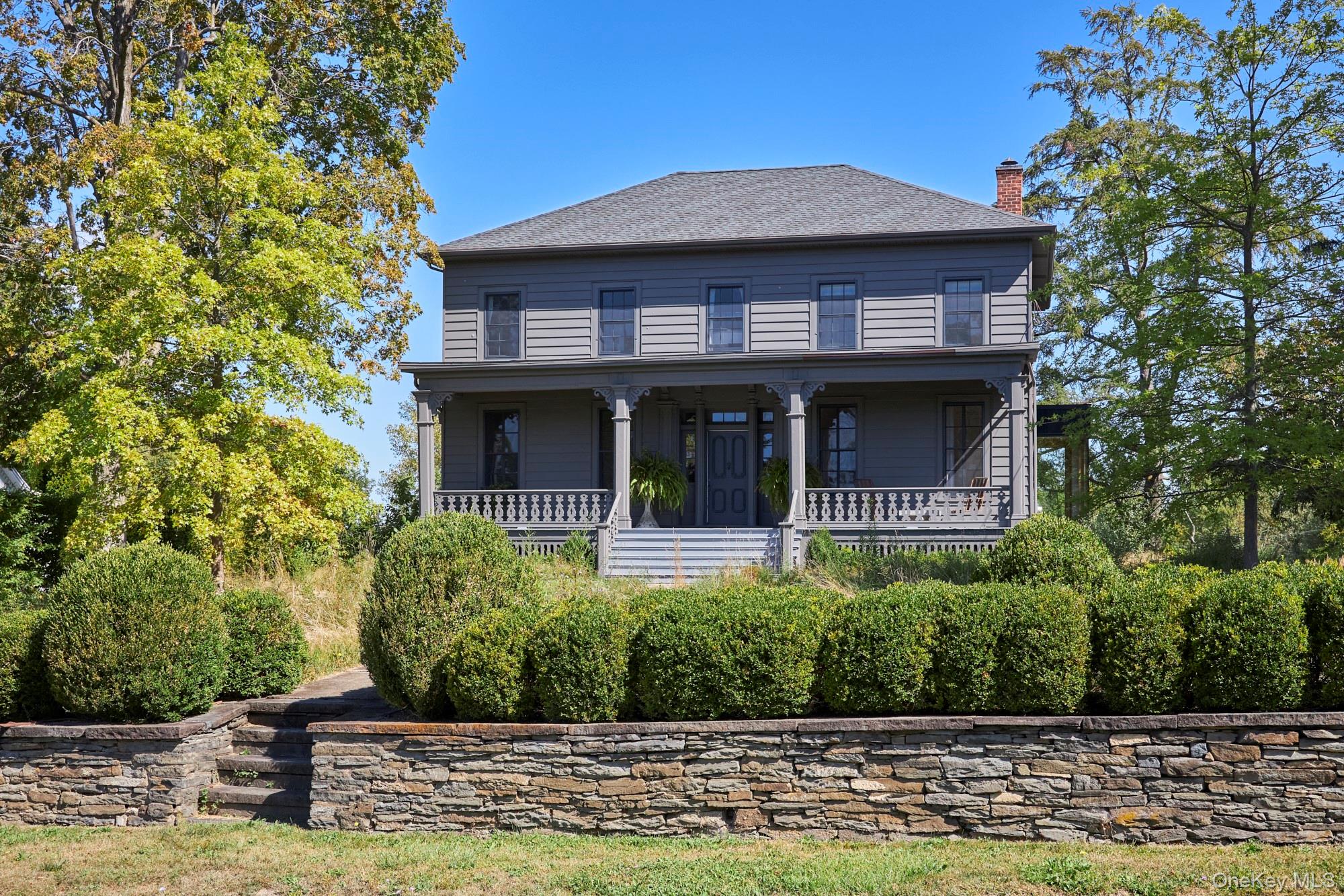 View of front of property featuring a chimney, a porch, and a shingled roof