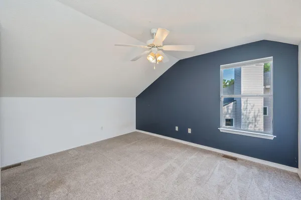 an empty room with windows and fan
