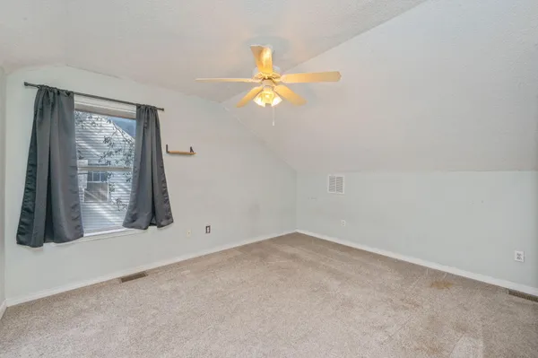 an empty room with windows and fan