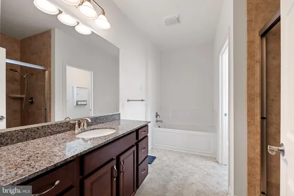 a bathroom with a granite countertop sink a large mirror and a bathtub