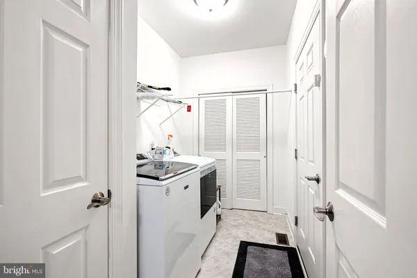 a bathroom with a granite countertop sink a washing machine and a shower