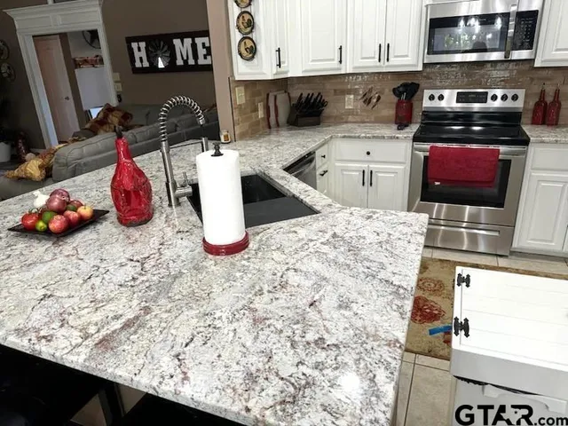 a kitchen with stainless steel appliances kitchen island granite countertop a sink and cabinets