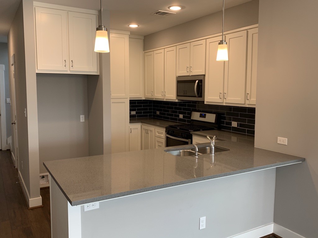 2509 South Grand Boulevard, Unit B Pearland, TX 77581 - Photo 5 of 13 a kitchen with stainless steel appliances granite countertop a sink a stove and a refrigerator