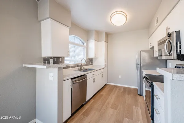 a kitchen with a sink cabinets stainless steel appliances and a window