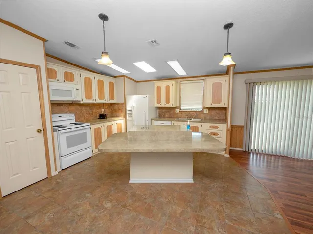 a large kitchen with granite countertop a large counter top a sink stainless steel appliances and cabinets