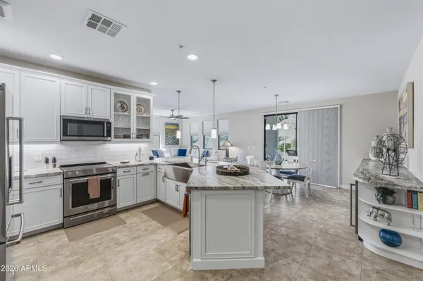 a kitchen with stainless steel appliances granite countertop a sink a stove and white cabinets