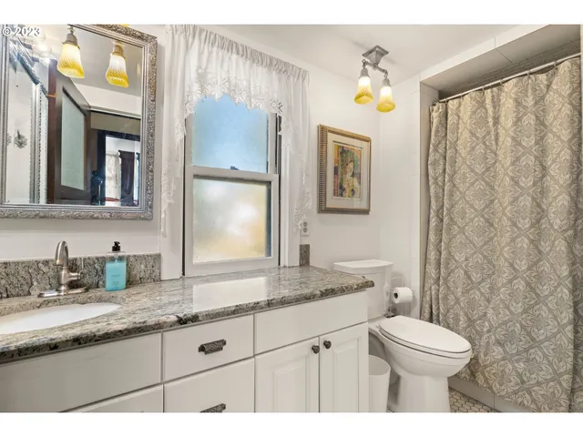 a bathroom with a granite countertop toilet sink and mirror