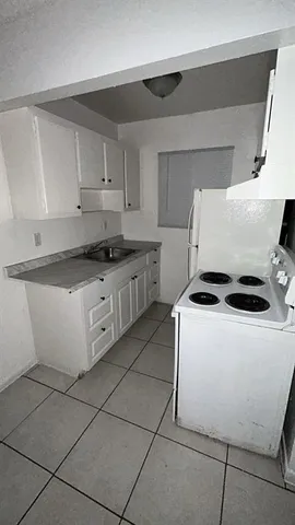a kitchen with granite countertop a sink a stove top oven and white cabinets