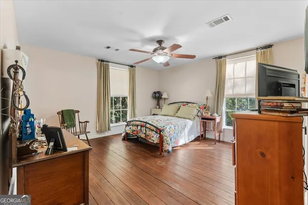 a bedroom with a bed wooden floor and a flat tv screen