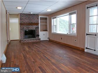 202 Wickford Road Havertown, PA 19083 - Photo 7 of 12 an empty room with wooden floor a fireplace and windows